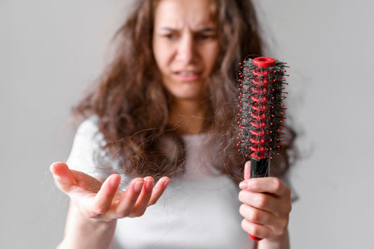 Woman looking at the hair on her hands that broke out while combing.